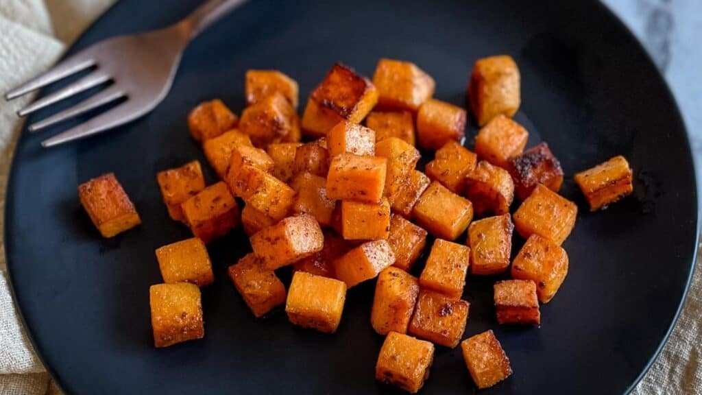 Sauteed sweet potatoes on a black plate.