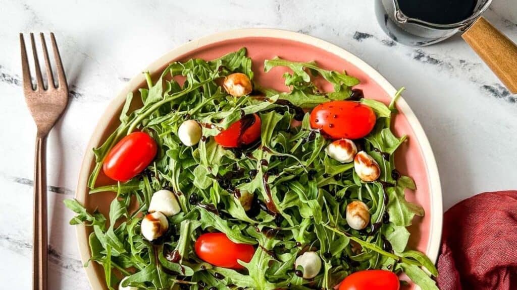 Balsamic reduction drizzled over an arugula salad with cherry tomatoes and mozzarella balls.