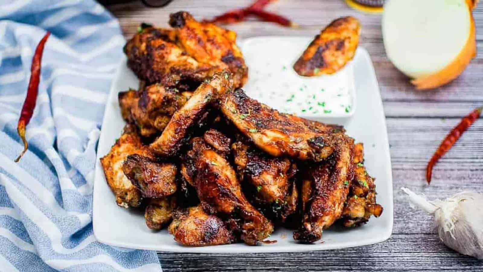 Air fryer bbq wings on a white plate with ranch dipping sauce.