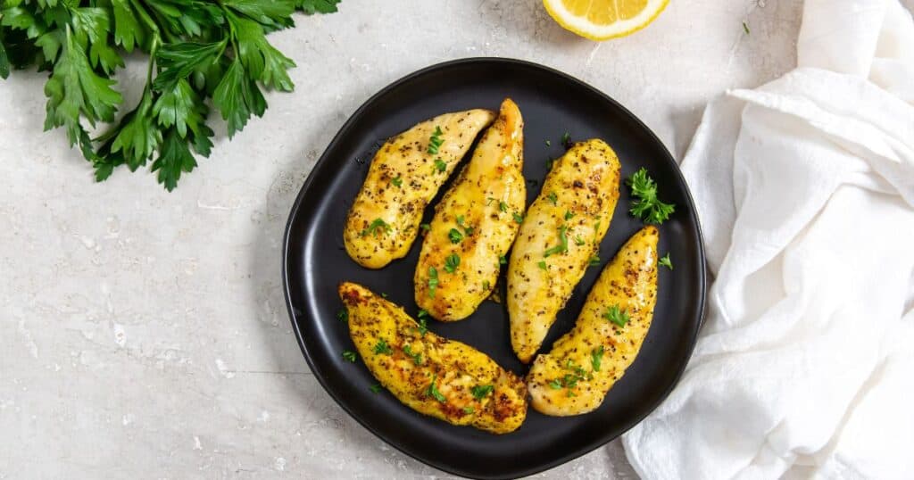 air fryer lemon pepper chicken tenders on a black plate.