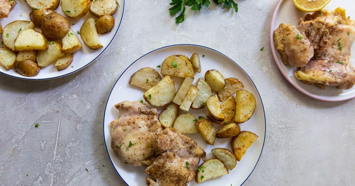 Juicy Air Fryer Chicken Thighs and Potatoes on a white plate with parsley and a fork.