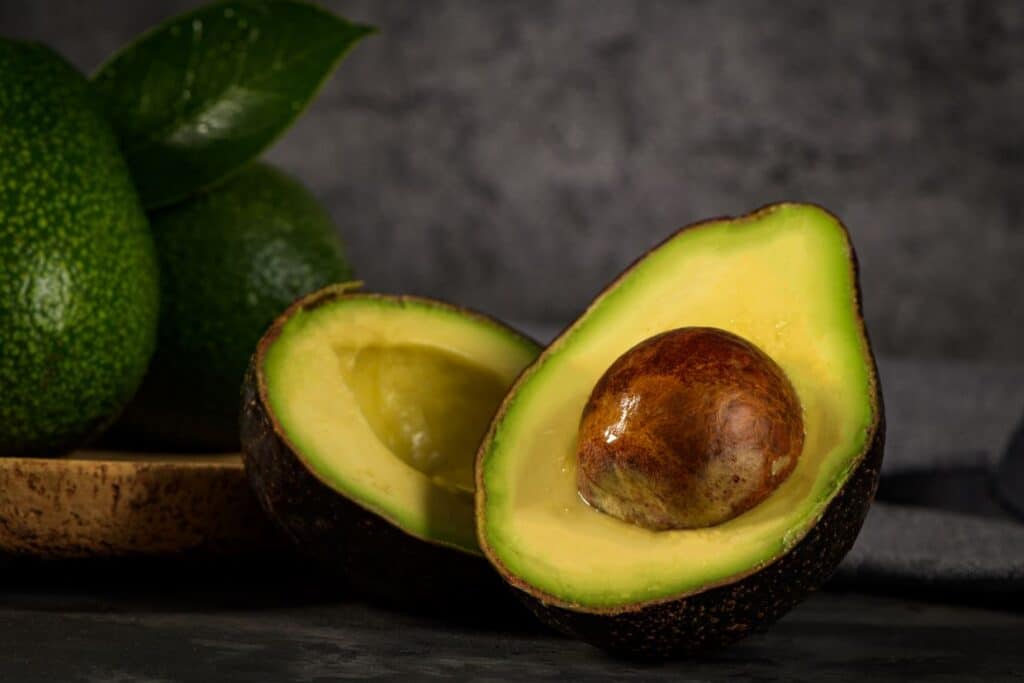 Two halves of an avocado with a grey background.