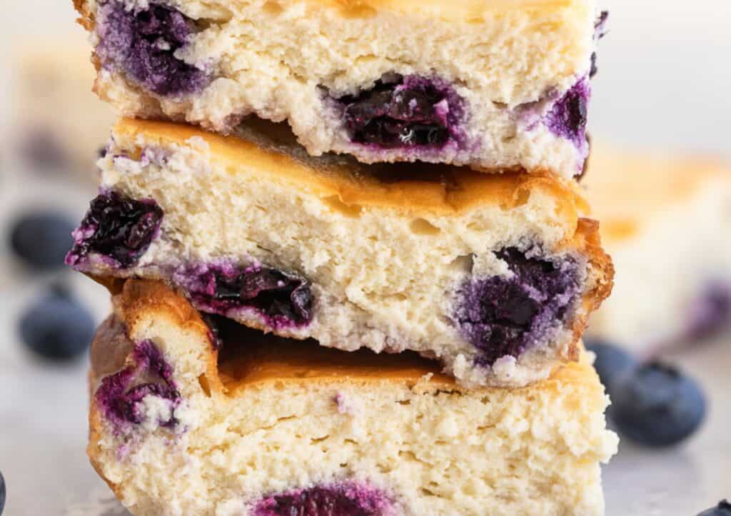 A stack of three blueberry cheesecake bars.
