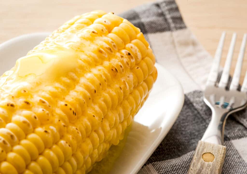 Buttered corn on the cob on a white plate.
