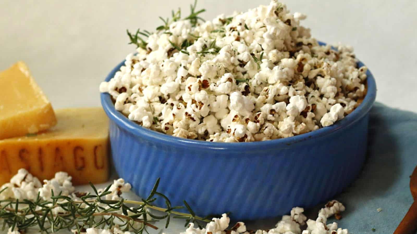 Popcorn with rosemary and Asiago cheese in a blue bowl.