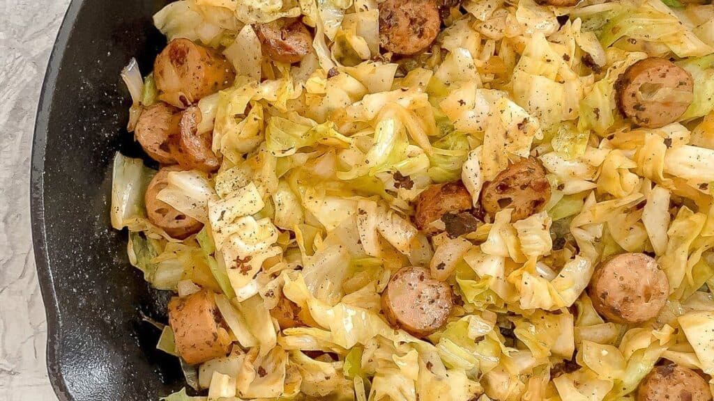 Chicken sausage and cabbage in a cast iron skillet.