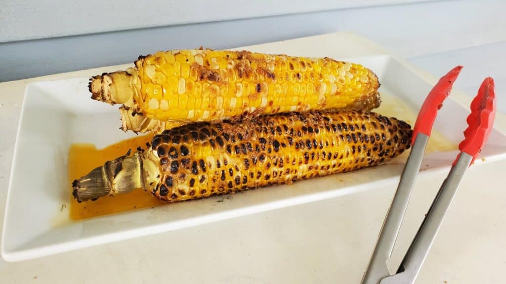Chipotle grilled corn cobs on a white tray.