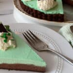 Chocolate mint tart slice on a white plate with a fork.