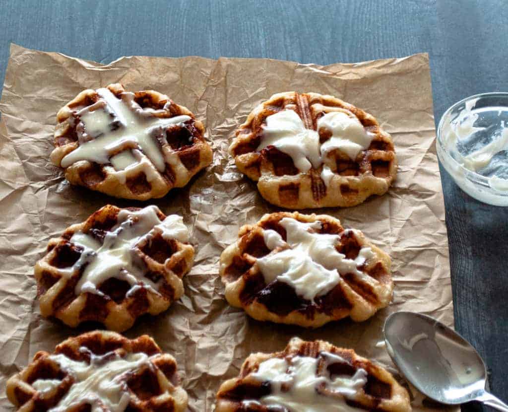 Cinnamon roll waffles with frosting on a baking sheet.