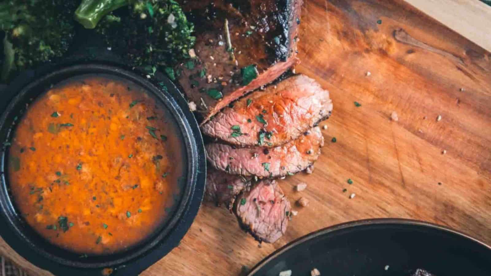 Overhead shot of sliced steak with ramiken filled with cowboy butter.