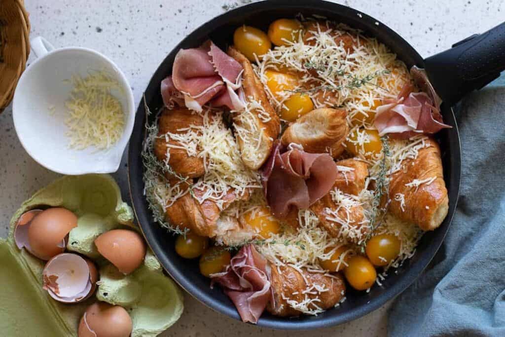 Overhead view of a croissant breakfast casserole in a skillet ready to be baked