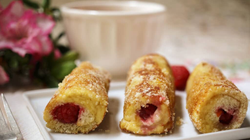 Raspberry French toast rolls on a white plate.