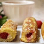 Raspberry French toast rolls on a white plate.