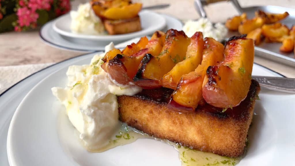 Grilled peaches and poundcake on a white plate.