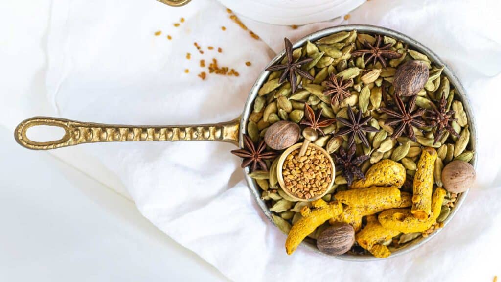 Whole spices inside a golden bowl.