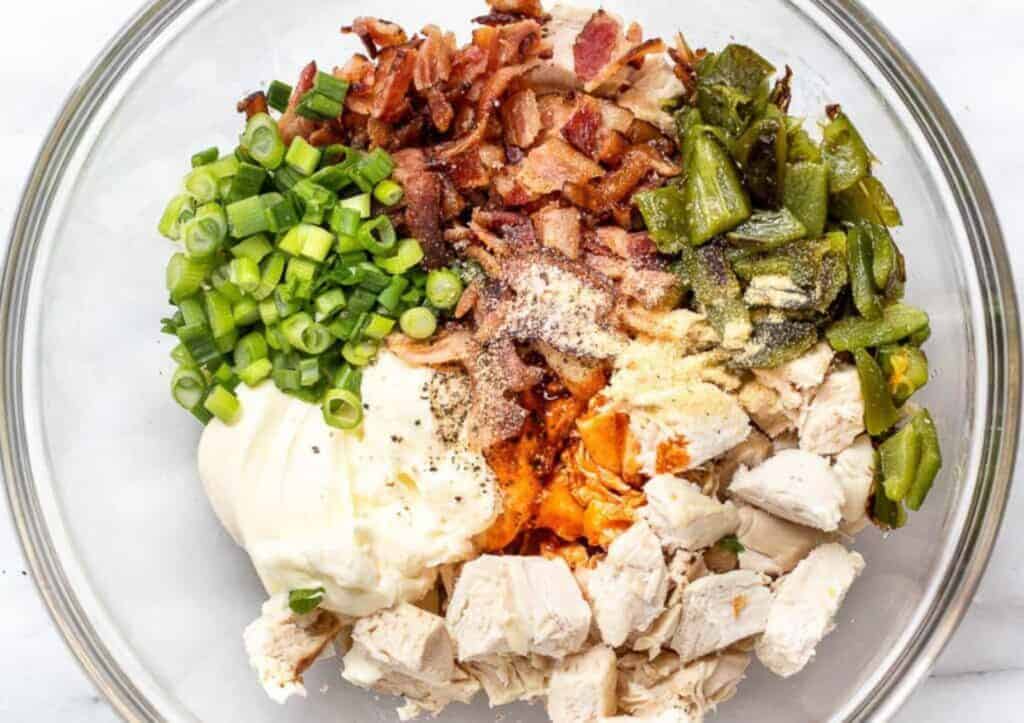 A glass bowl of jalapeño popper chicken salad ingredients.