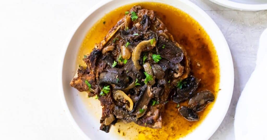 Slow Cooker Keto Pork Chops on a white plate with mushrooms and onions.