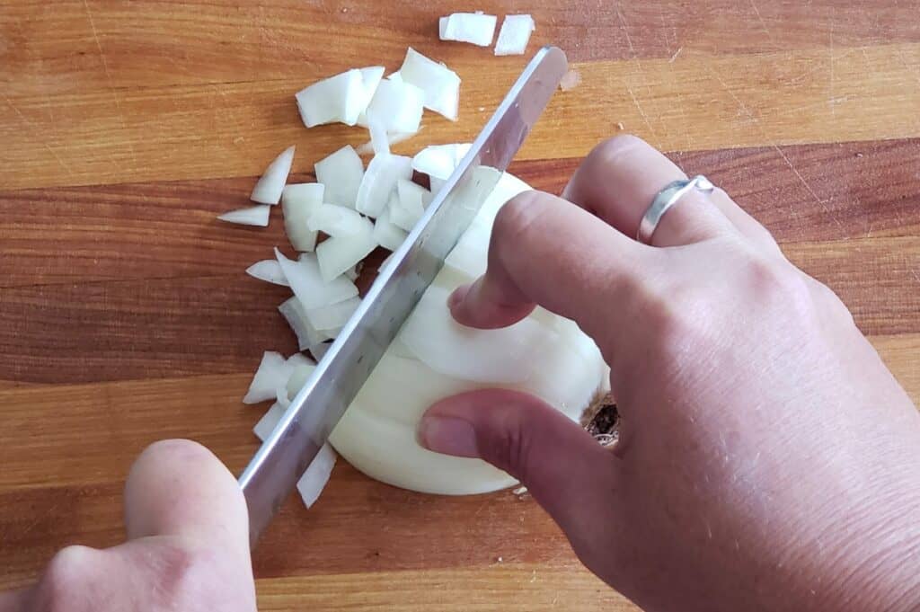 Knife doing the final cut to dice an onion.