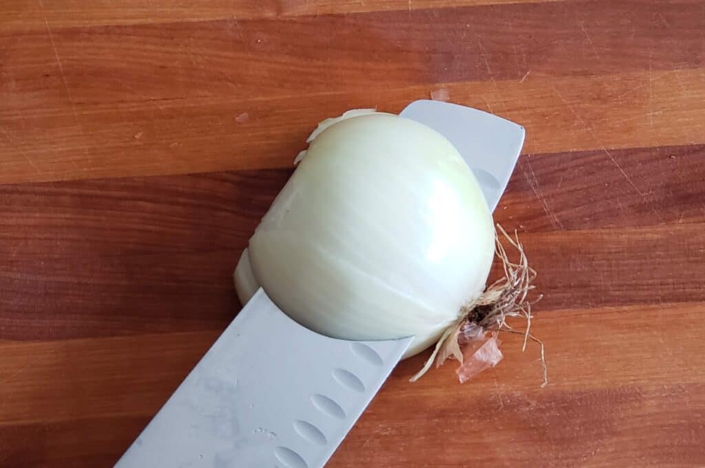 Knife slicing into an onion from overhead.