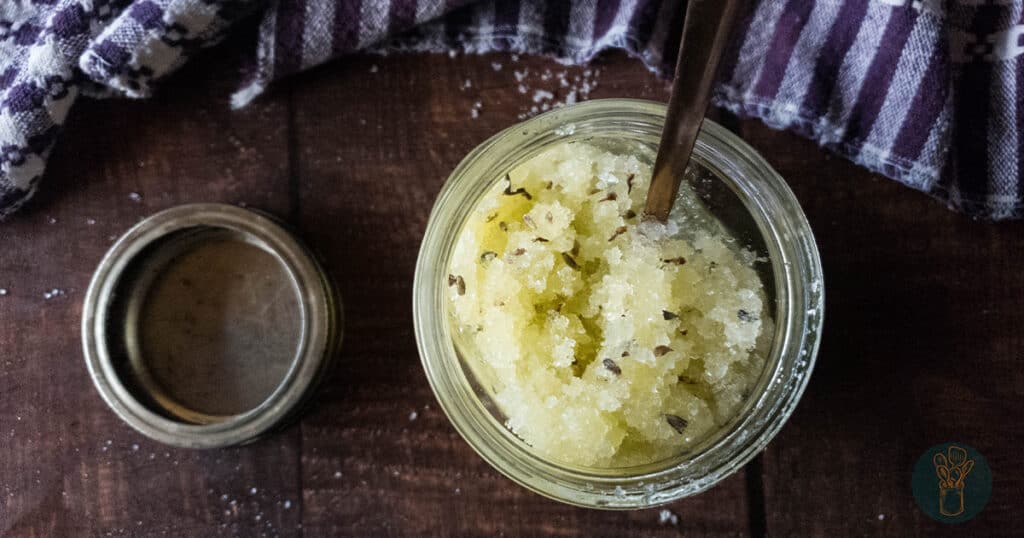 epsom salt scrub with lavender pieces in glass jar with wooden spoon from above wide view