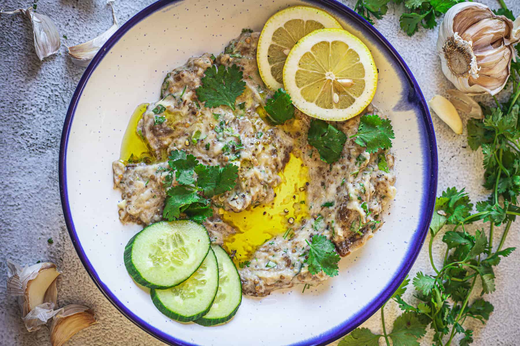 Baba ganoush on a plate with parsley and lemon.