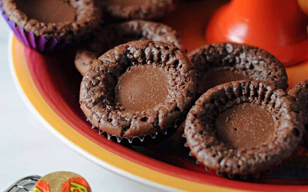 Brownie bites with peanut butter cups inside on a platter.