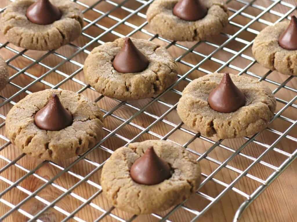 Peanut butter cookies topped with hershey's kisses on a cooling rack.