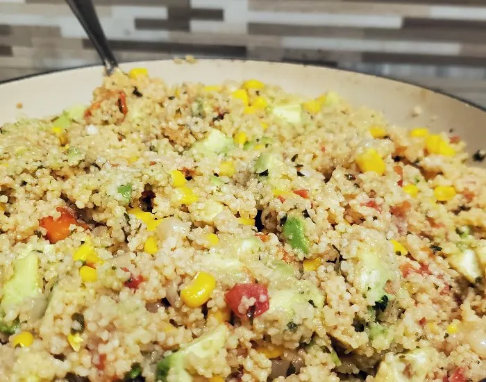 Image shows a closeup of an enameled cast iron pan filled with a vegan couscous salad.