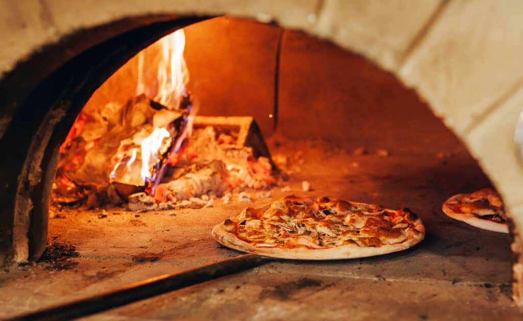 Two pizzas in a firewood pizza oven.