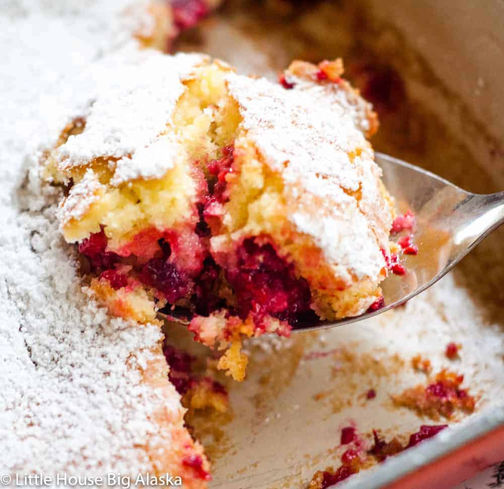 Raspberry buckle in a pan with a spoon scooping some out of the pan. 