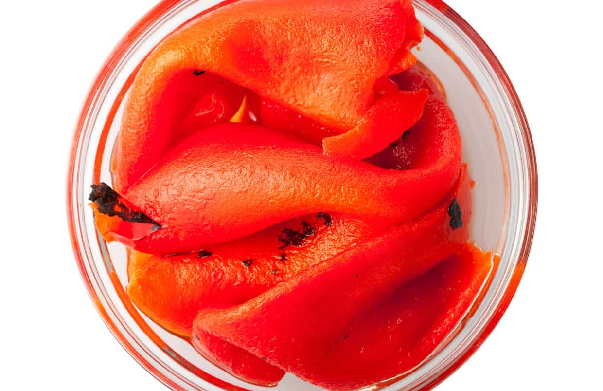 Roasted peppers peeled and stored in a glass jar. 