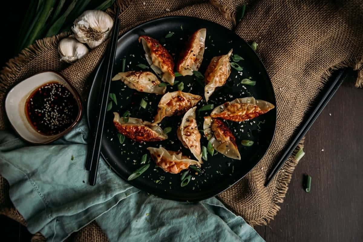 Salmon dumplings on a black plate with a green onions.