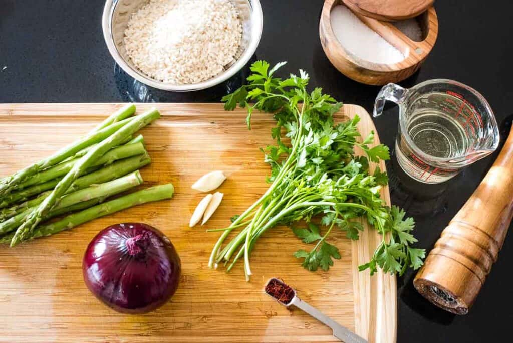 Ingredients for risotto on and around a cutting board.