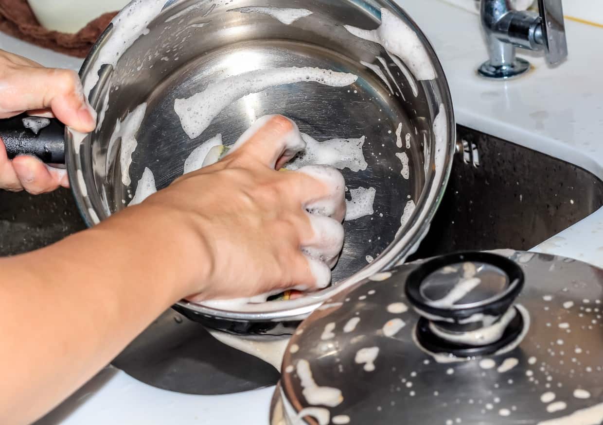 https://fooddrinklife.com/wp-content/uploads/2023/05/Stainless-steel-pan-being-scrubbed-clean.jpg