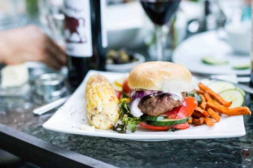 Lamb burger on a bun on an outood picnic table. 