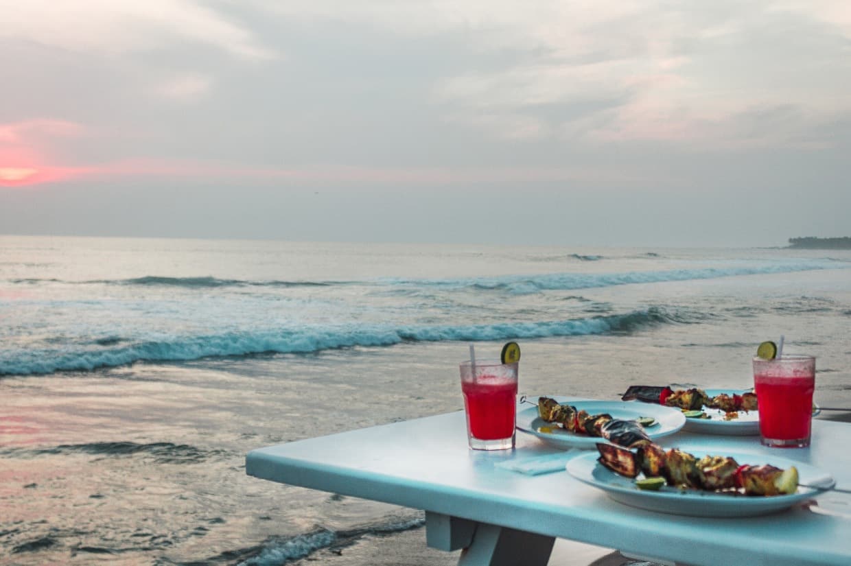 Table with food and cocktails on the beach.