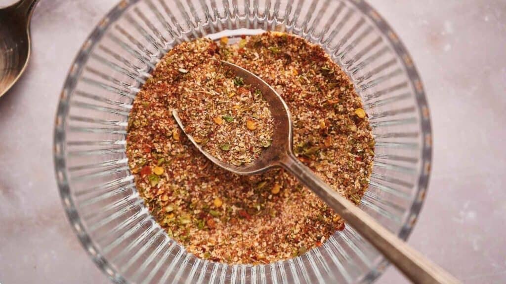 Taco seasoning in a glass bowl with a teaspoon in it.