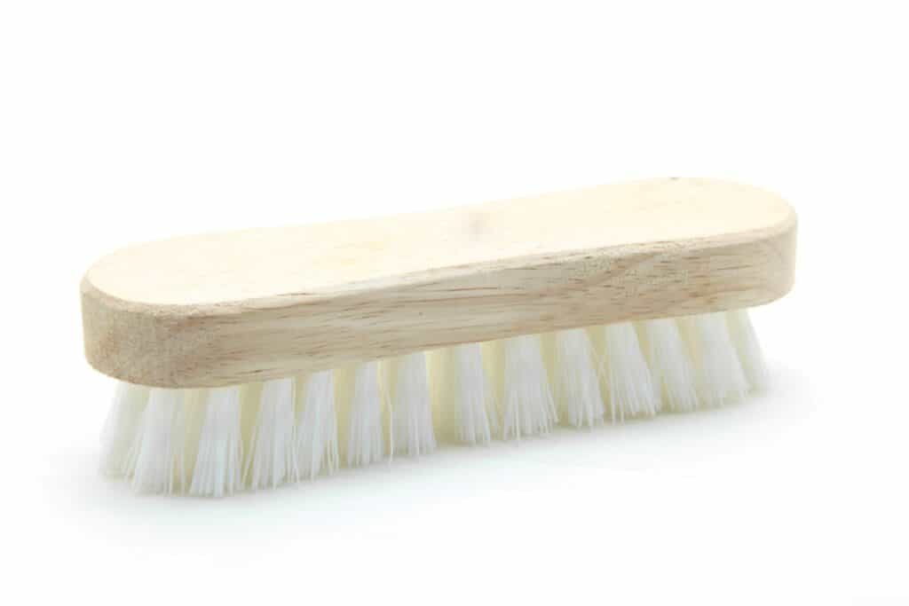 Wooden scrub brush with white bristles.