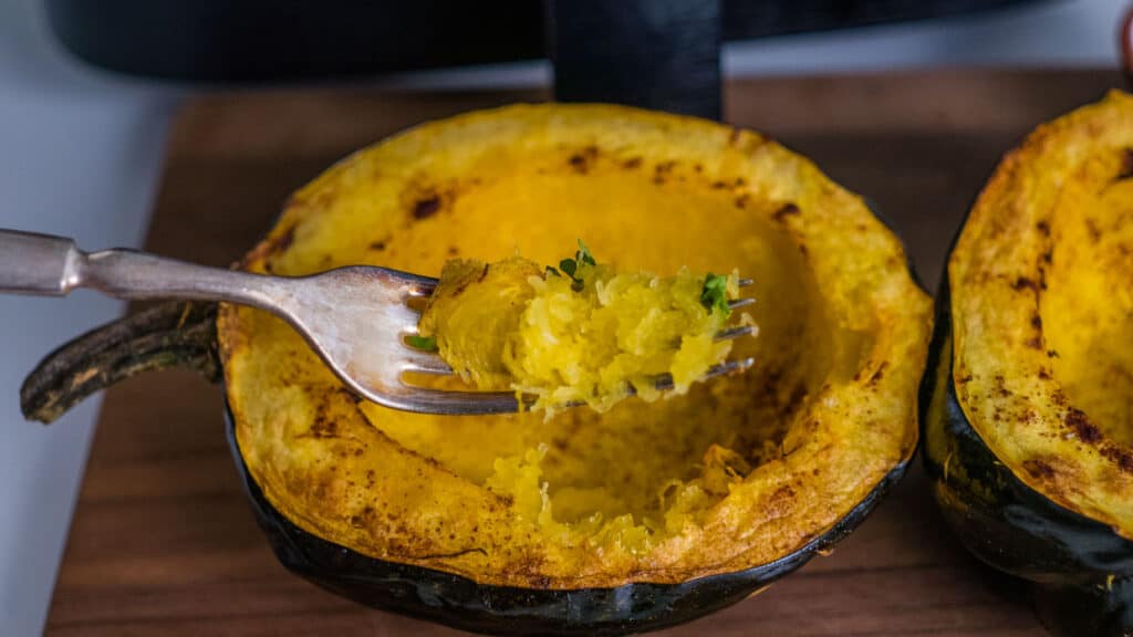 Acorn squash after air frying with some of the insides scooped up on a fork.