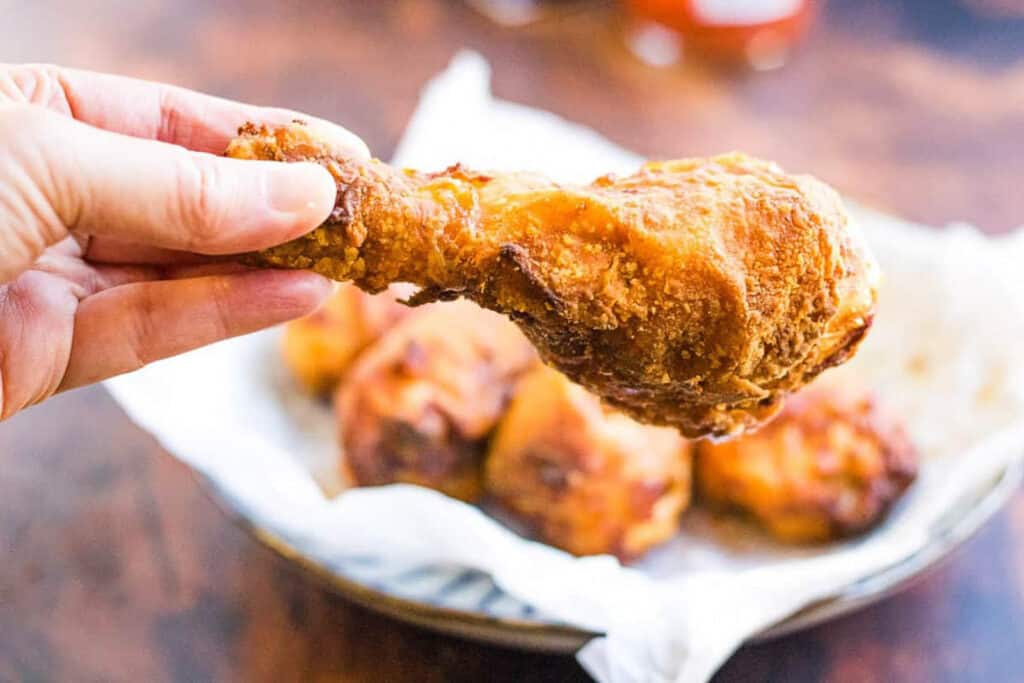 hand holding an air fryer fried buttermilk chicken leg.