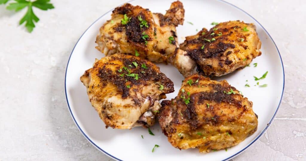 air fryer blackened chicken thighs on a white plate with parsley.