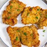 air fryer breaded chicken thighs on a white plate with parsley.
