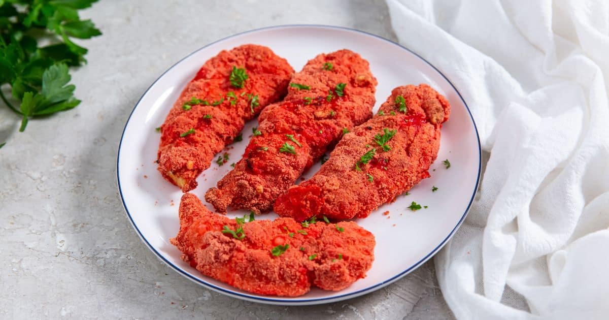 Air Fryer Flamin' Hot Cheetos Chicken Tenders on a white plate with parsley.