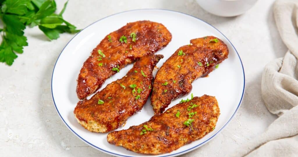 honey BBQ chicken tenders on a white plate.