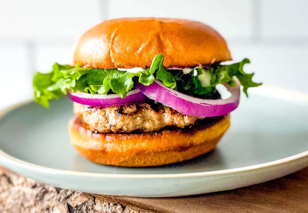 Turkey burger topped with lettuce and onion on a light blue plate.