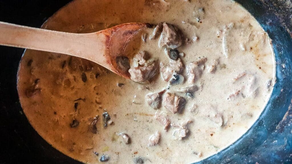 Crockpot beef stroganoff with wooden spoon