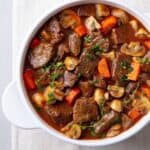 A picture of beef stew with mushrooms carrots and thyme.