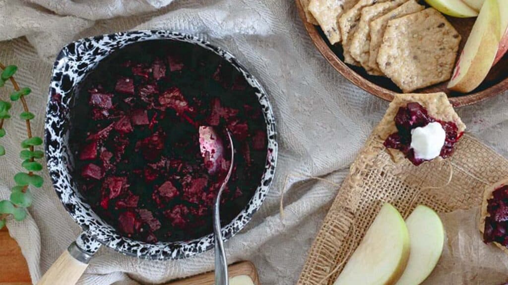 Spiced orange beet apple chutney in a small sauce pot with a spoon.