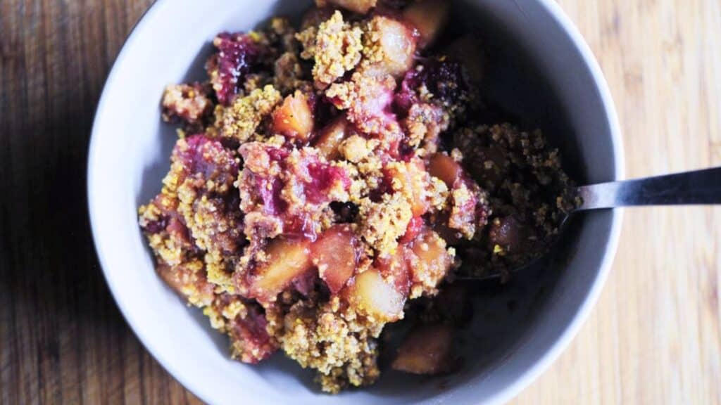 A white bowl filled with berry crumble.
