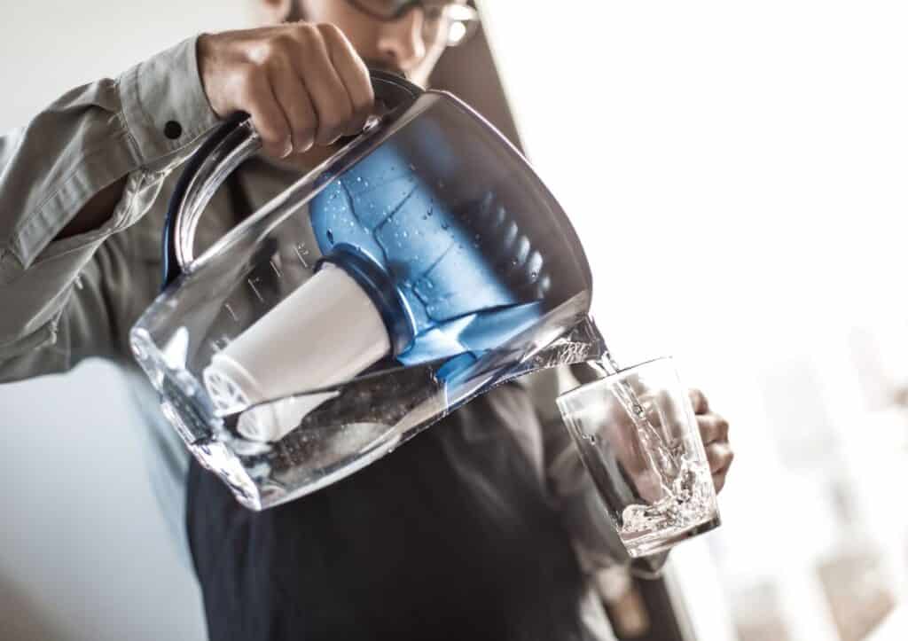 Man pouring filtered water into a glass.
